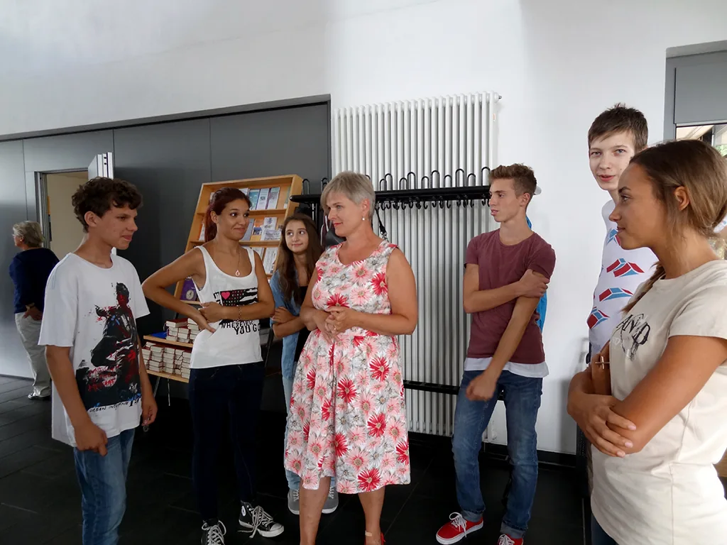 Neue Schülerinnen und Schüler stehen mit ihren Eltern im Foyer.